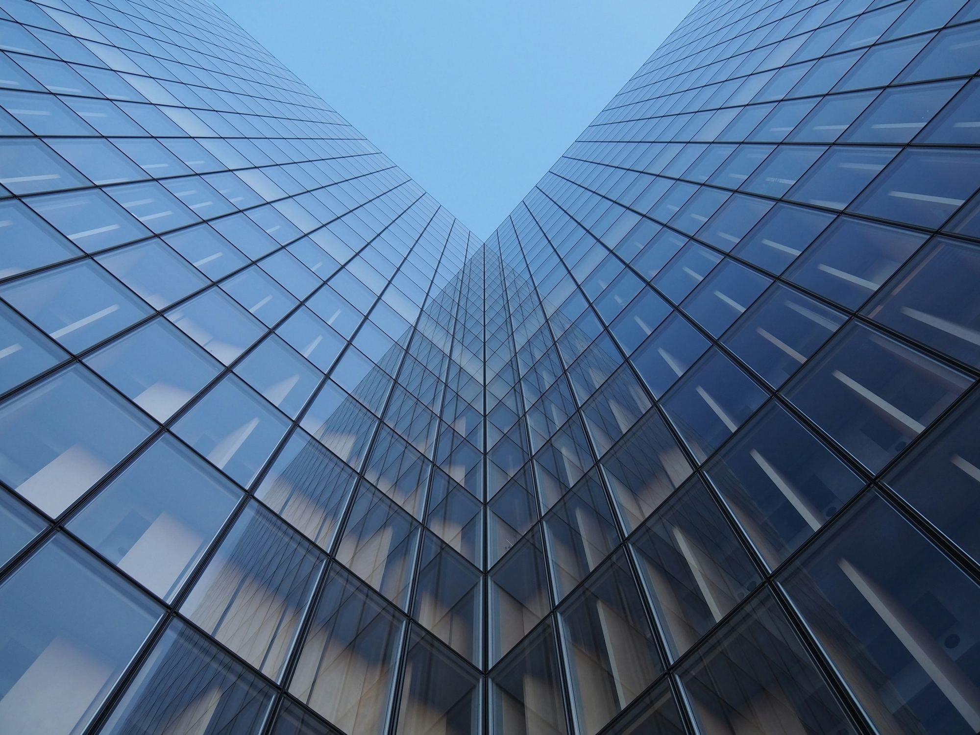Two glass towers seen from the street, rising into a pale sky.
